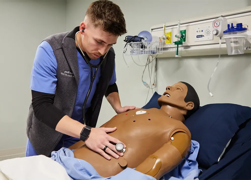 A physician assistant student listens to cardiac sounds on a patient simulator